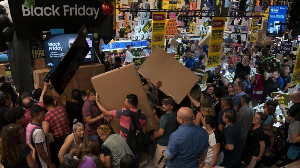 Clientes com TVs compradas durante uma liquidação da Black Friday em São Paulo em 2023