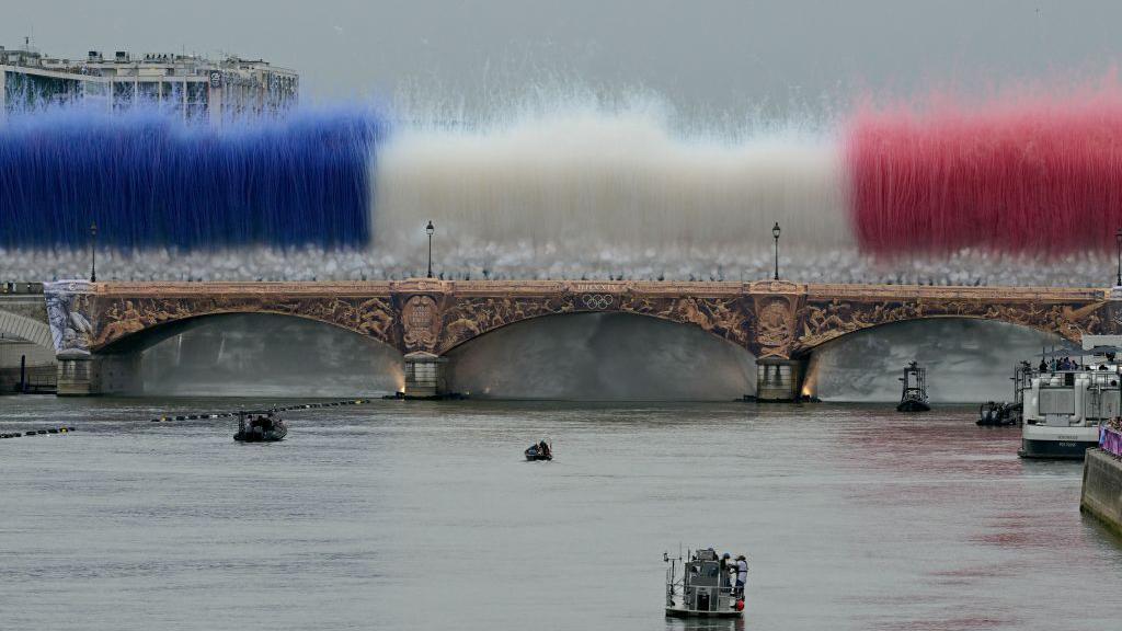 Humo de colores que forman la bandera de Francia sobre un puente del río Sena en París durante la inauguración de los Juegos Olímpicos 2024
