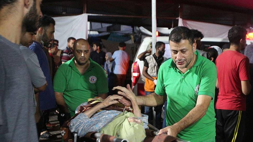 Paramédicos llevan una mujer mayor herida al hospital Al Shifa 