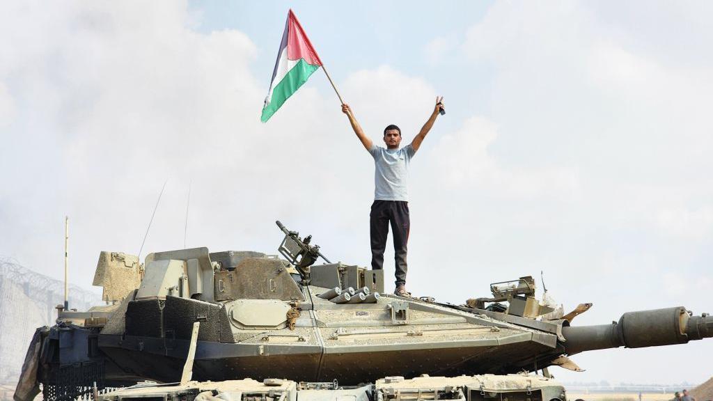 Un hombre del brazo armado de Hamás ondea la bandera palestina