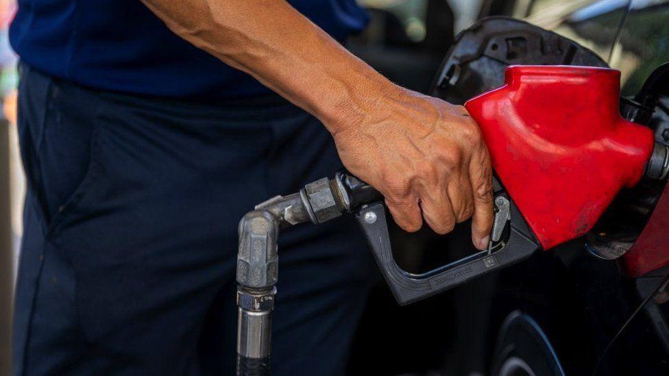 Homem abastacendo carro em posto de combustíveis