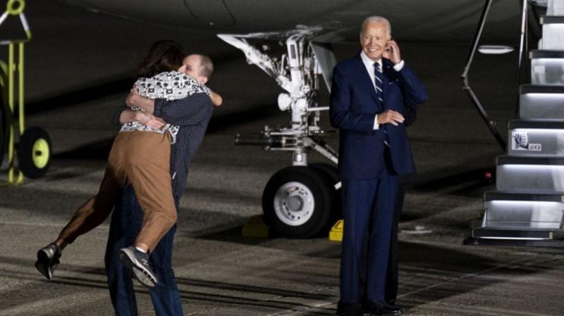 Evan Gershkovich, que aparece na foto abraçado à mãe, e Joe Biden ao seu lado 