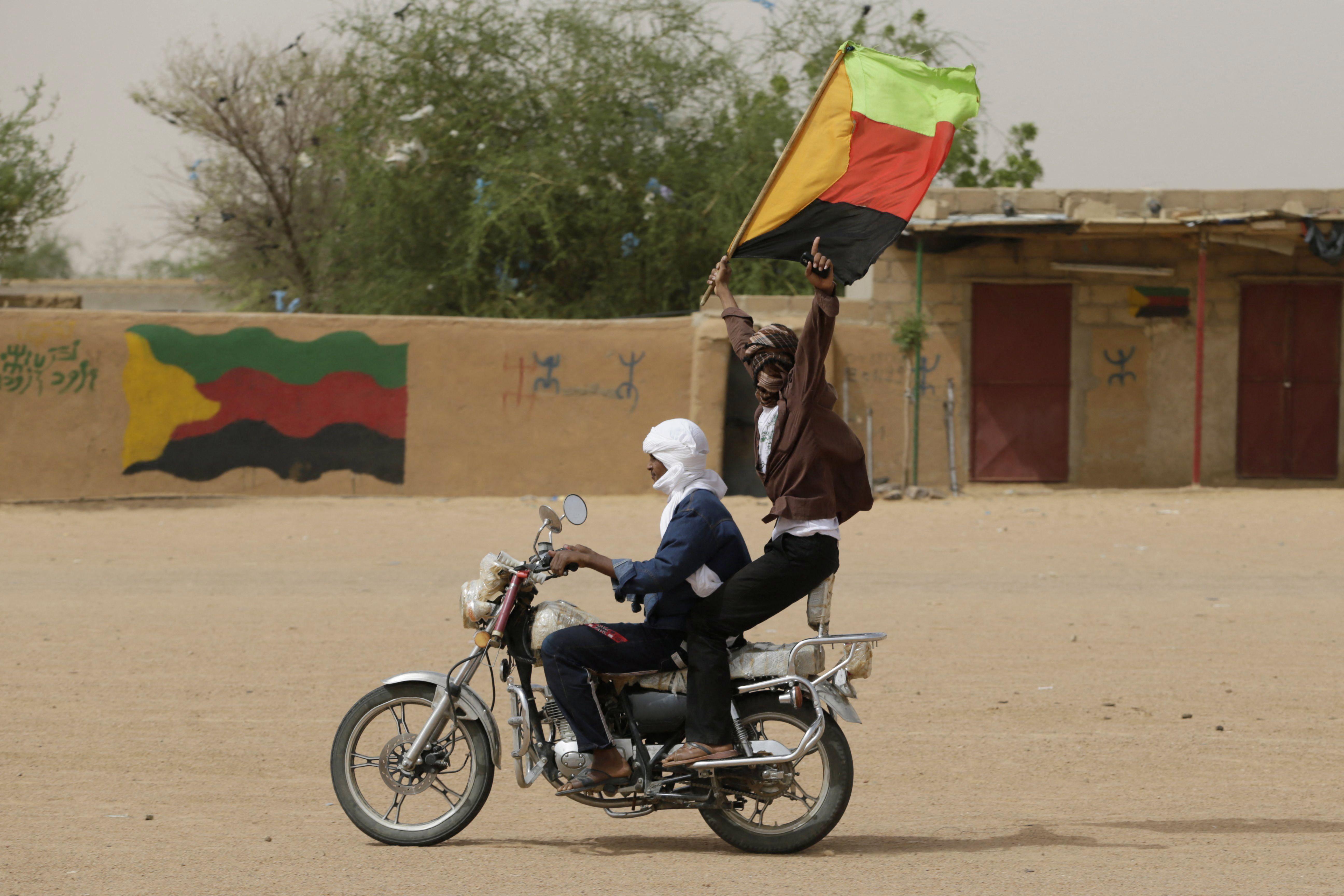 رجل طوارقي يلوّح بعلم الحركة الوطنية لتحرير أزواد (MNLA) خلال مظاهرة دعم للحركة في 28 تموز/يوليو 2013 في كيدال، شمال مالي.