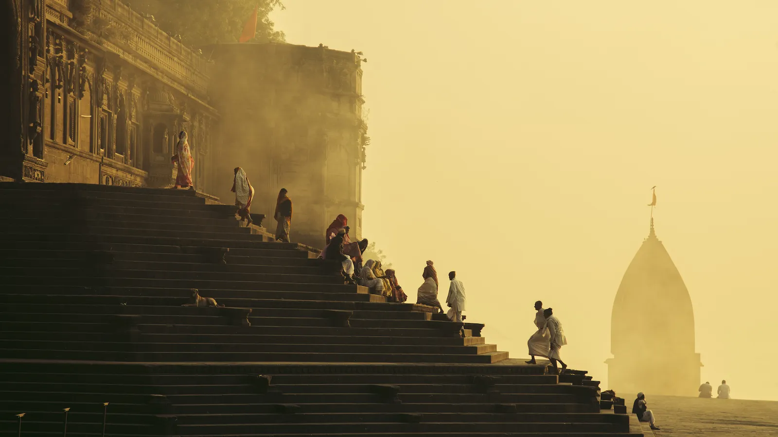 Vista de pessoas sentadas ou subindo um escadaria contra o pôr do sol 