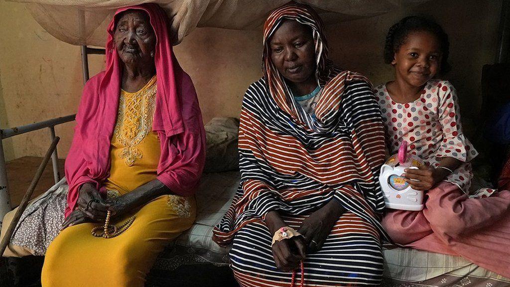 Zubaida sentada com a avó e uma das filhas