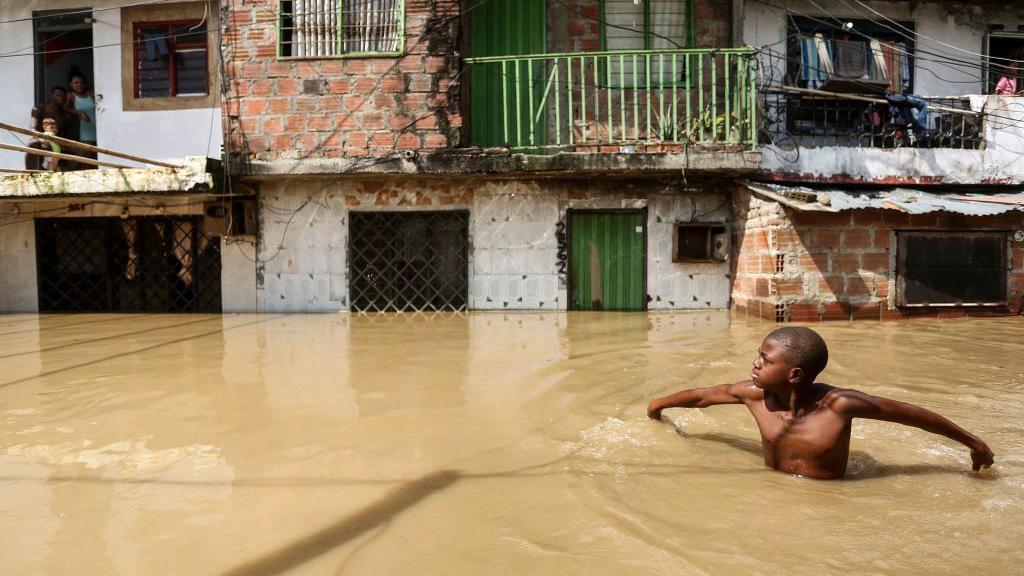 Um menino caminha por uma rua inundada em Cali, Colômbia, em 11 de novembro de 2022