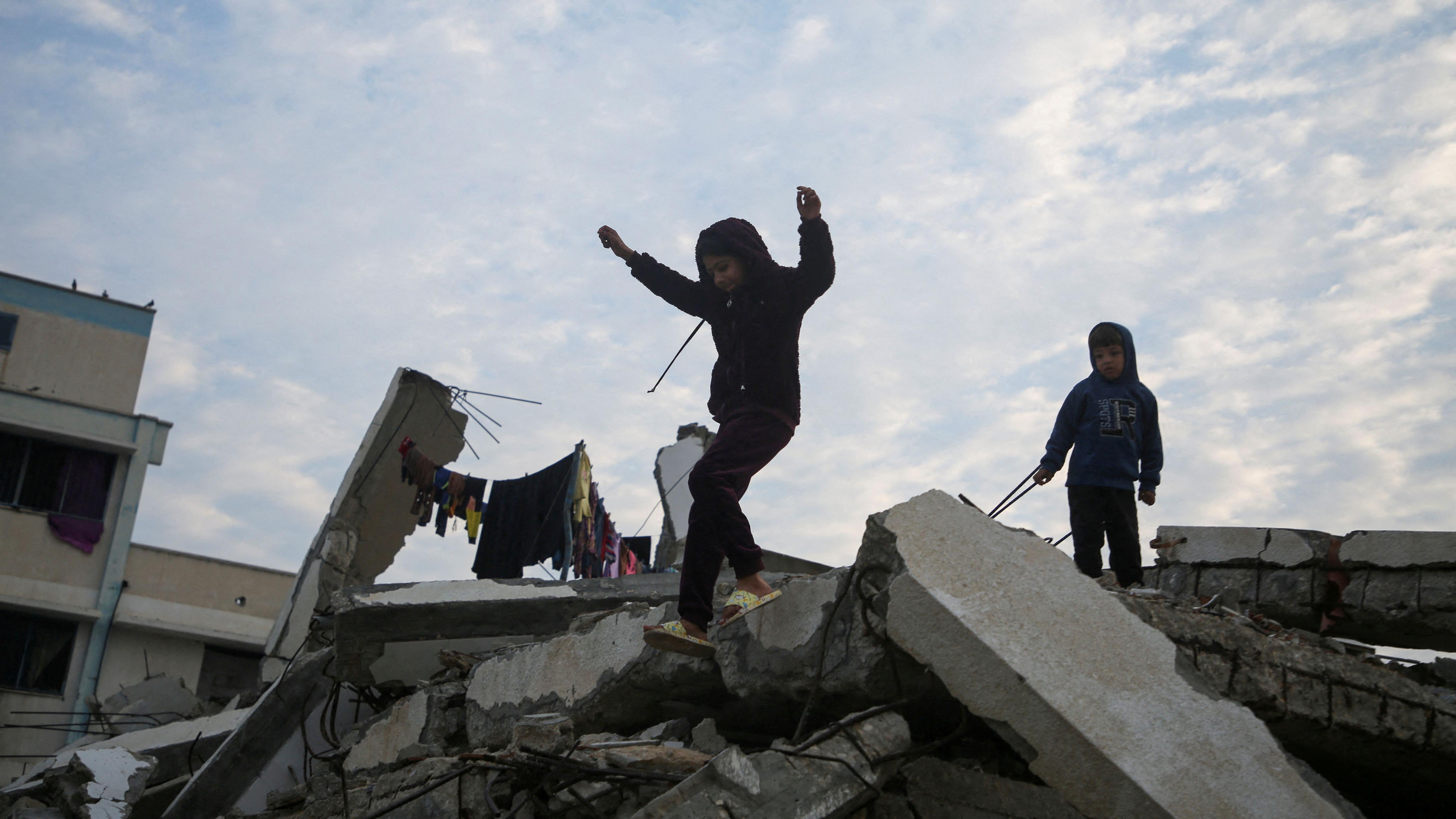 Uma criança palestina salta dos escombros de um prédio destruído em ataques israelenses anteriores