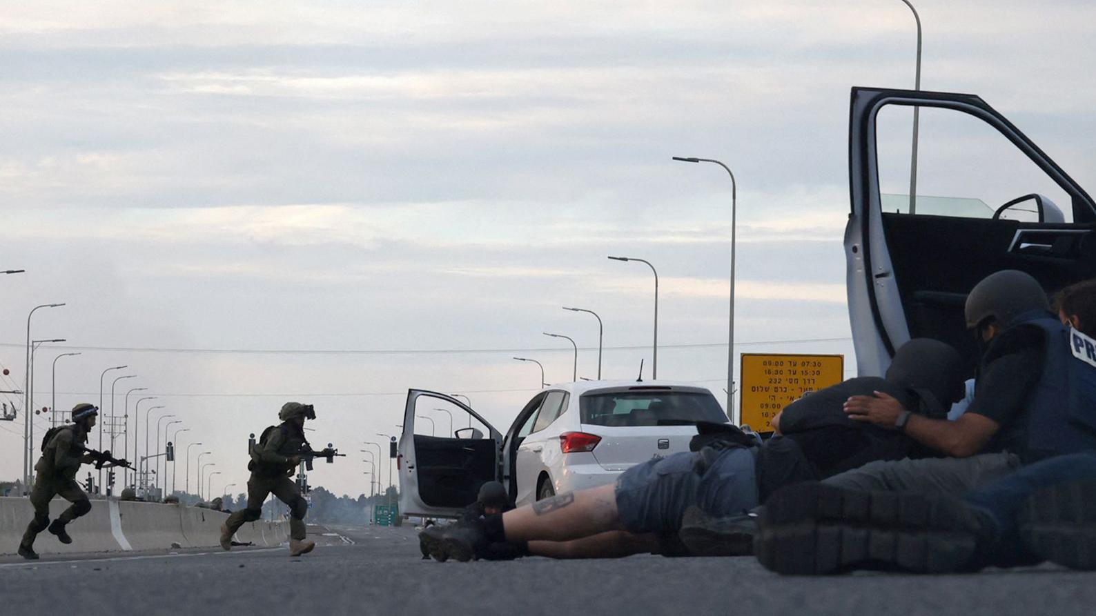 Periodistas se protegen detrás de los coches mientras los soldados israelíes toman posiciones durante los enfrentamientos con los combatientes palestinos cerca del kibutz Gevim, cerca de la frontera con Gaza el 7 de octubre de 2023