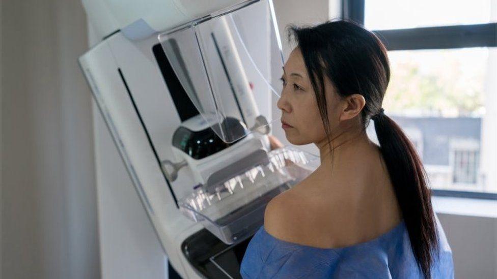 Mulher em frente a aparelho de mamografia
