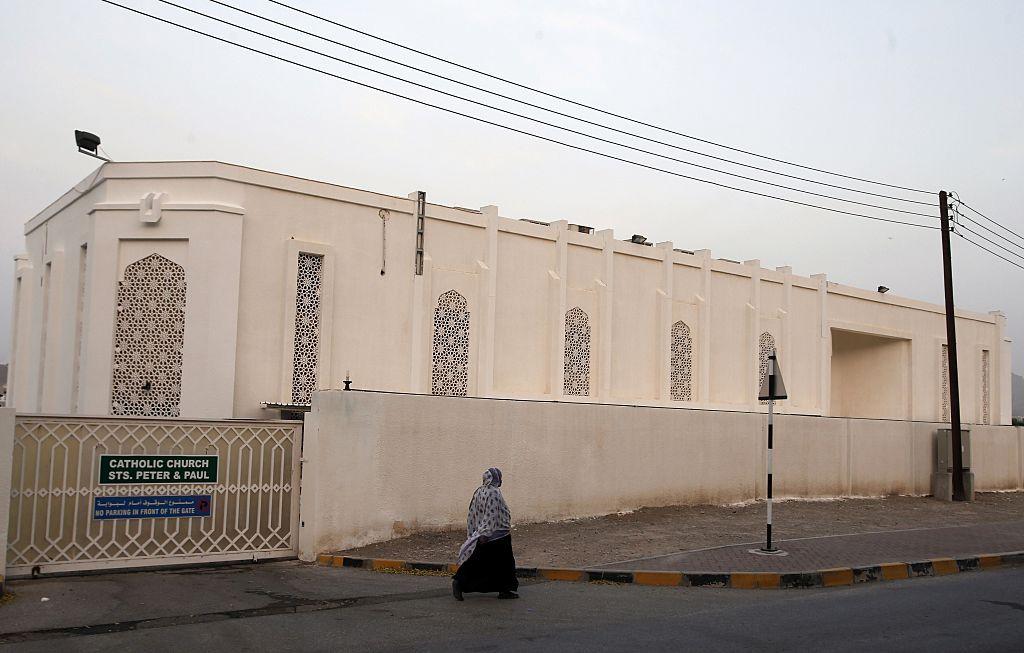 امرأة عمانية تسير أمام كنيسة القديسين بطرس وبولس الكاثوليكية في 22 فبراير/شباط 2015، في العاصمة العمانية مسقط