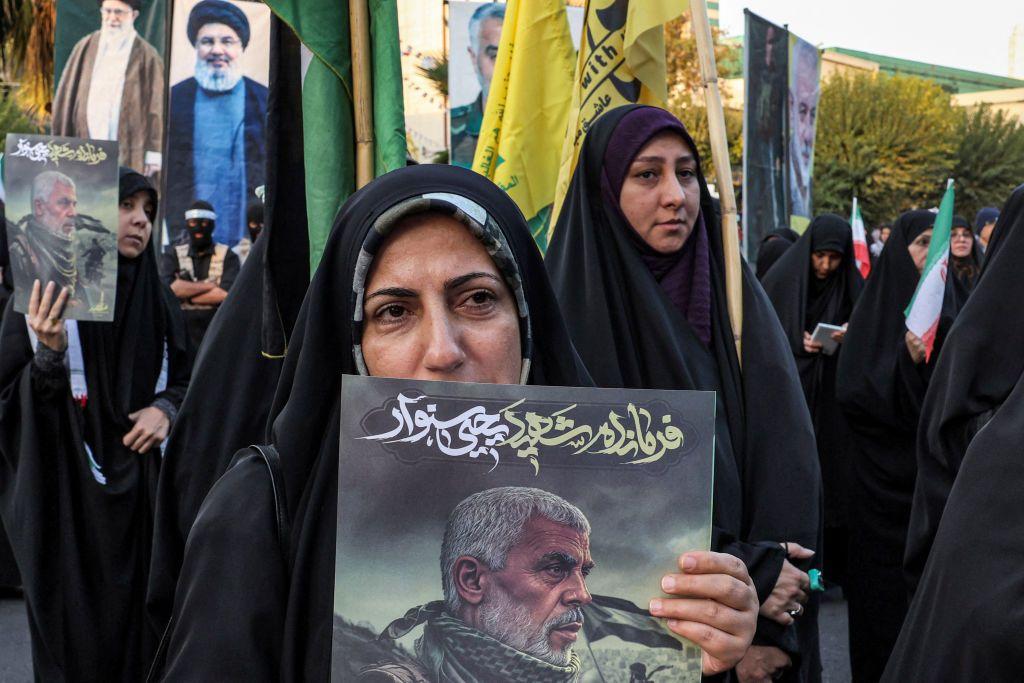 Una mujer porta un cartel con una imagen de Yahia Sinwar y otras de Nasralá y Jamenei en una manifestación en Irán.