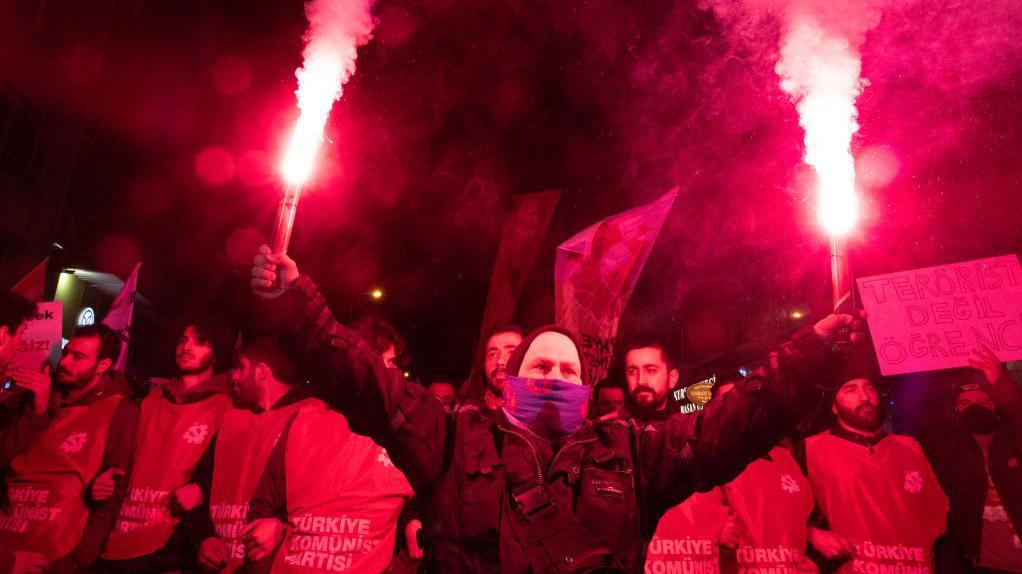 Protesters light flares during clashes on 23 March 2025 in the Turkish capital, Ankara