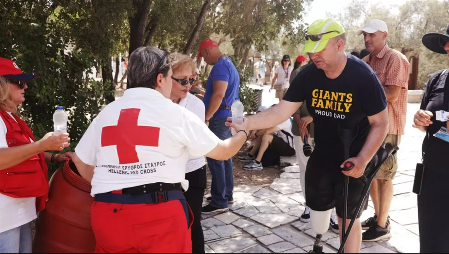متطوع يعطي الماء لزائر بالقرب من تل الأكروبوليس، خلال موجة حارة في أثينا، اليونان، 14 يوليو 2023.
