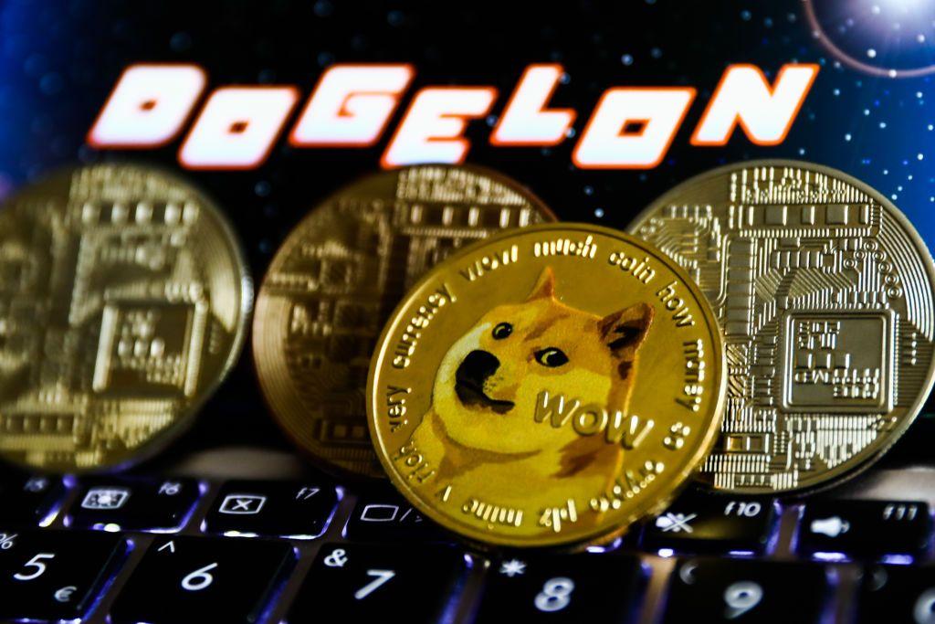 شعار عملة Dogelon Mars المشفرة المعروض على شاشة الهاتف ويظهر تمثيل Dogecoin في هذه الصورة التوضيحية التي تم التقاطها في كراكوف، بولندا في 2 نوفمبر 2021.