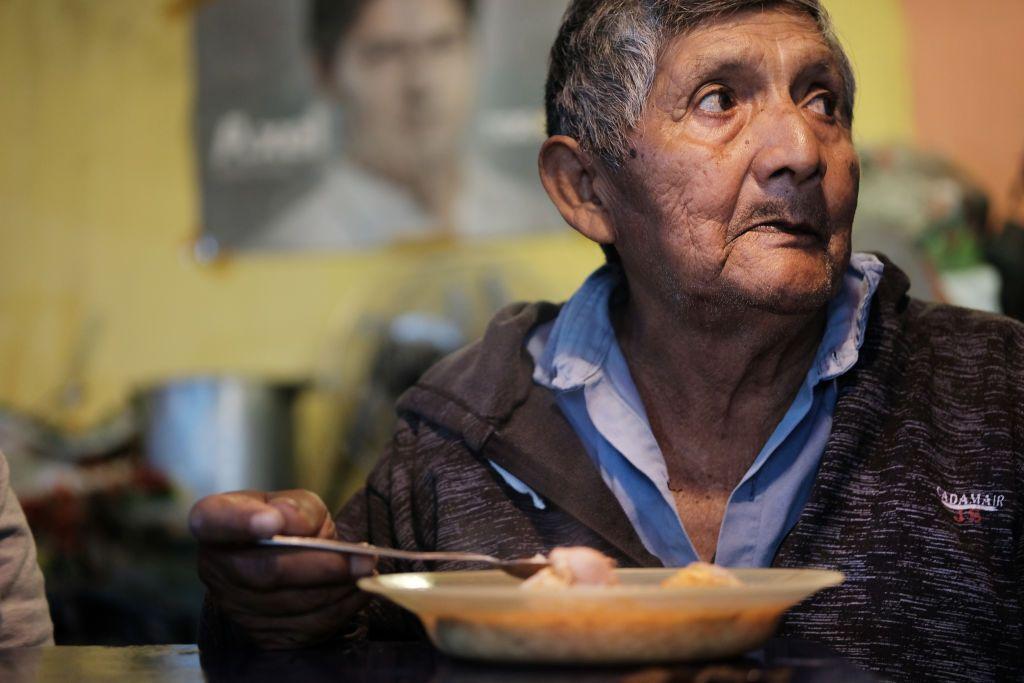 Adulto mayor comiendo en un barrio humilde de Buenos Aires, Argentina.