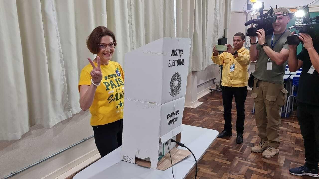 Cristina com blusa amarela numa cabine de votação 