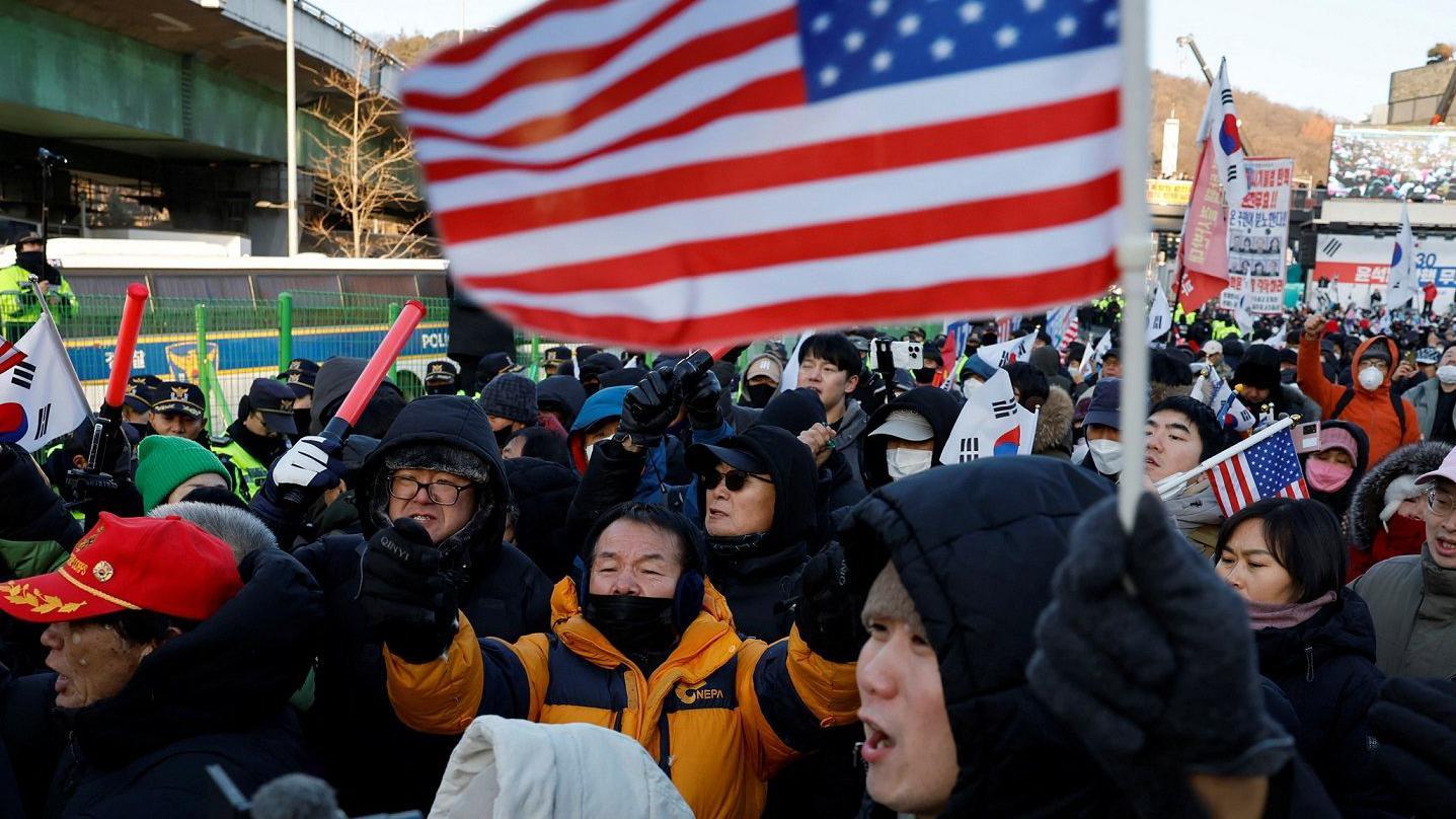 Протестувальники з прапорами США та Південної Кореї
