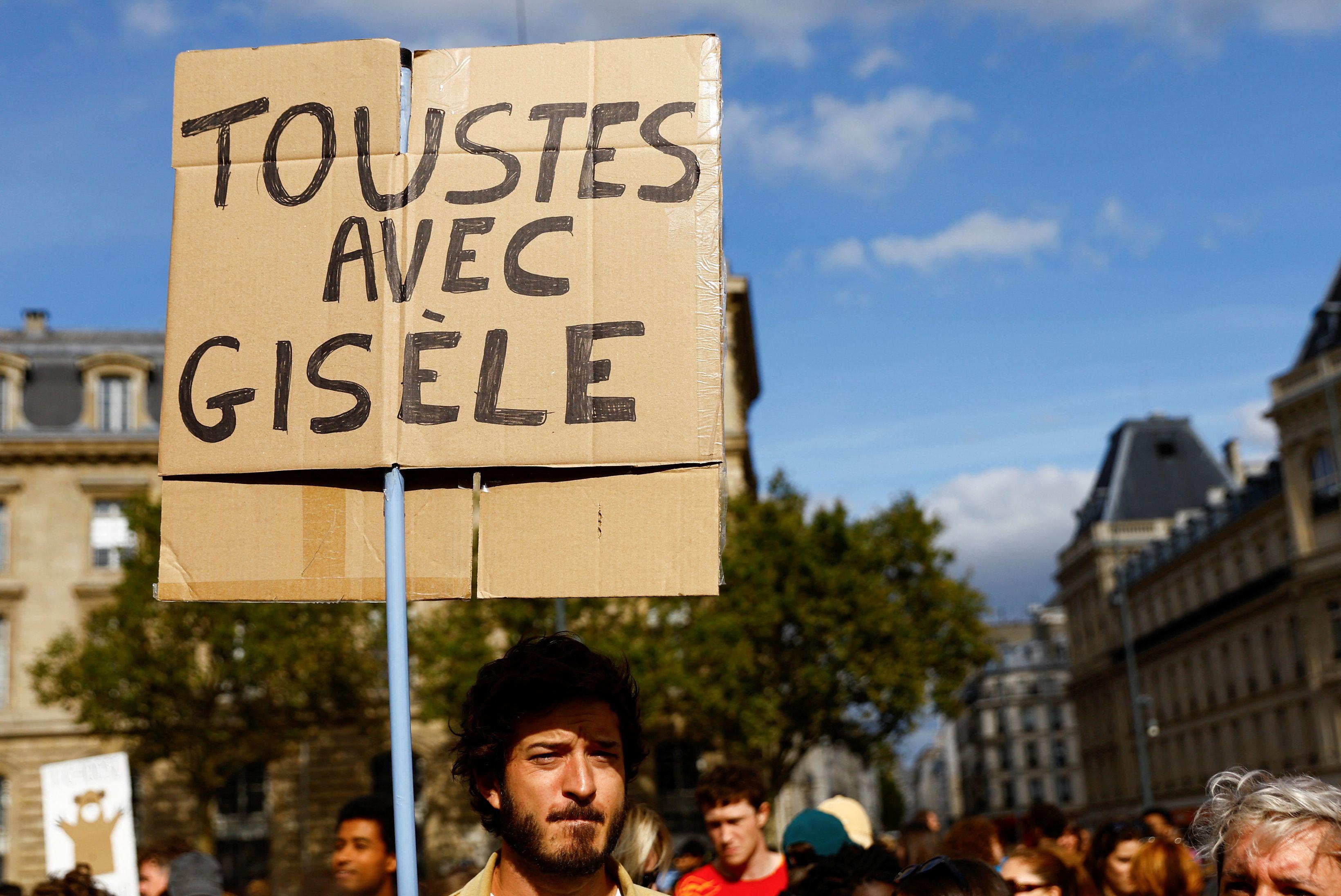 Un hombre con una pancarta que dice: "Todos con Gisèle".