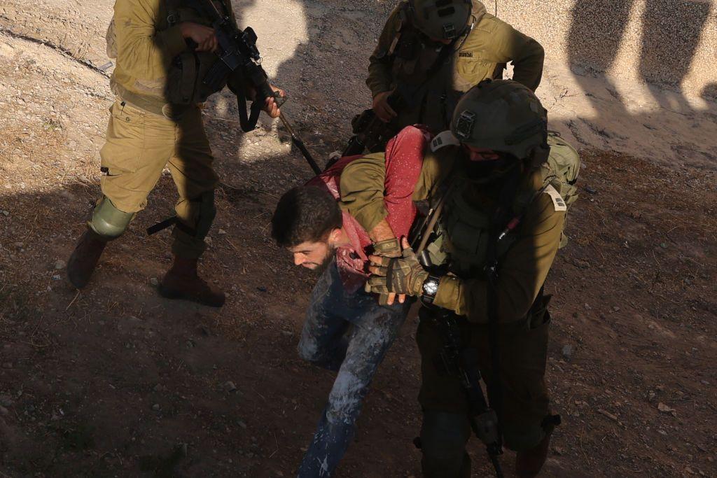 صورة لجندي إسرائيلي يعتقل فلسطيني أثناء إحدى المداهمات في الضفة الغربية