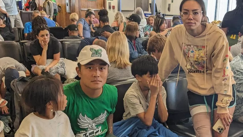 Tee Dang, com uma faixa na perna, e sua família posam para foto em abrigo lotado no Havaí 