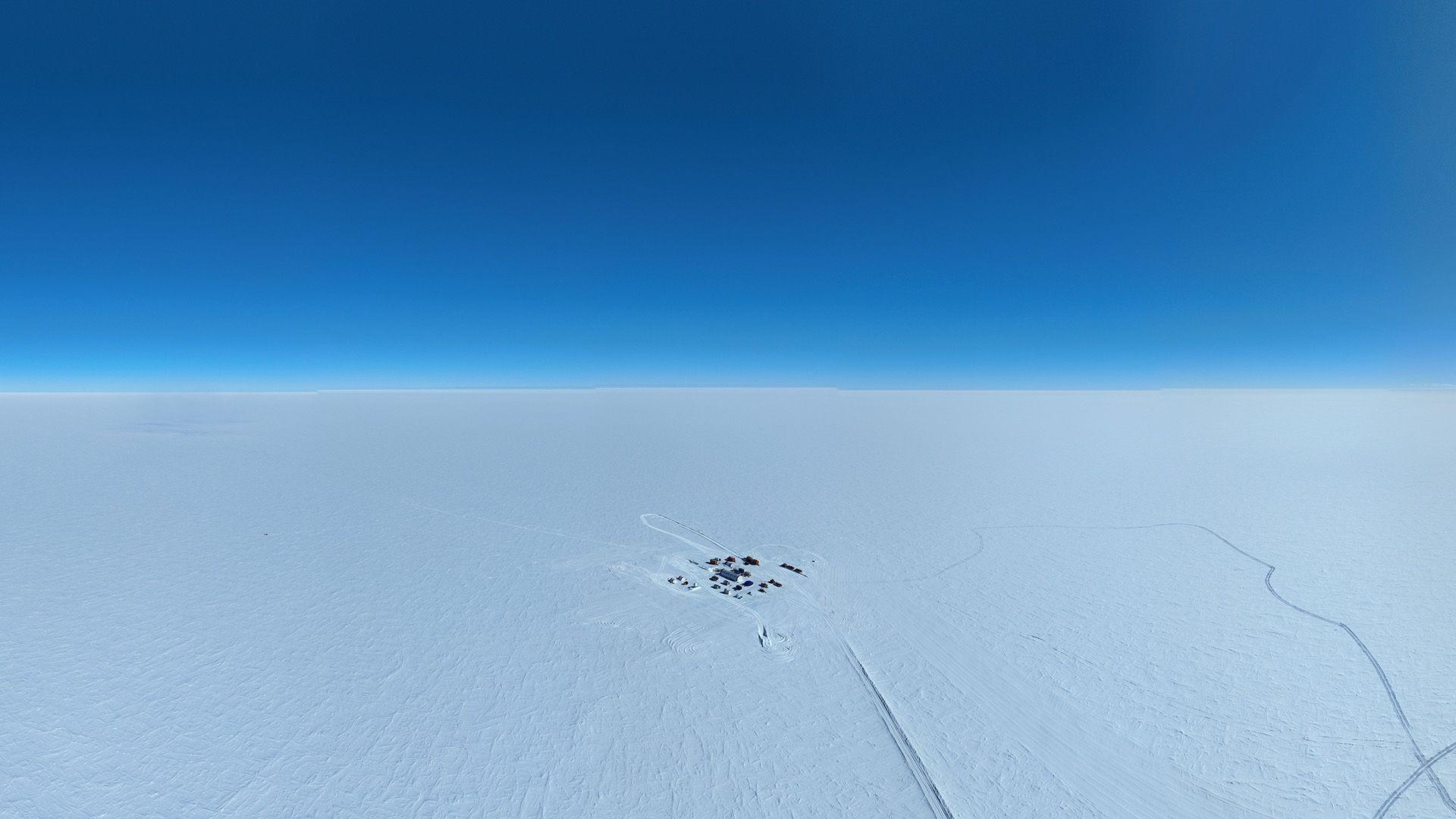 Uma vista aérea de um campo de investigação isolado numa vasta paisagem de gelo, onde os cientistas enfrentaram temperaturas de -35°C para perfurar o gelo.