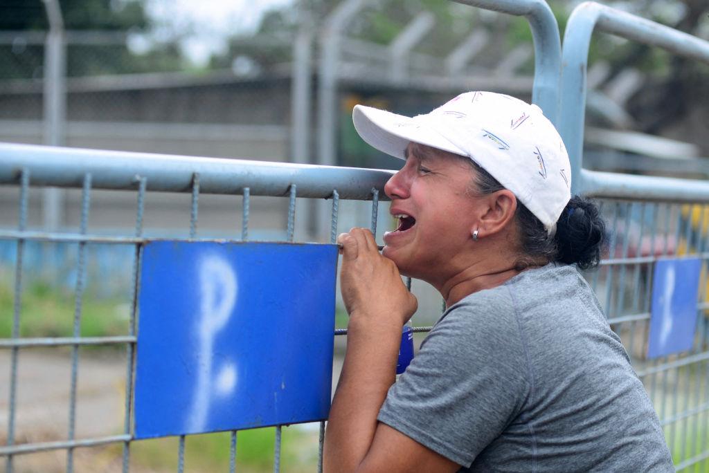 A woman cries at the gate of a prison where violence took place in Ecuador.