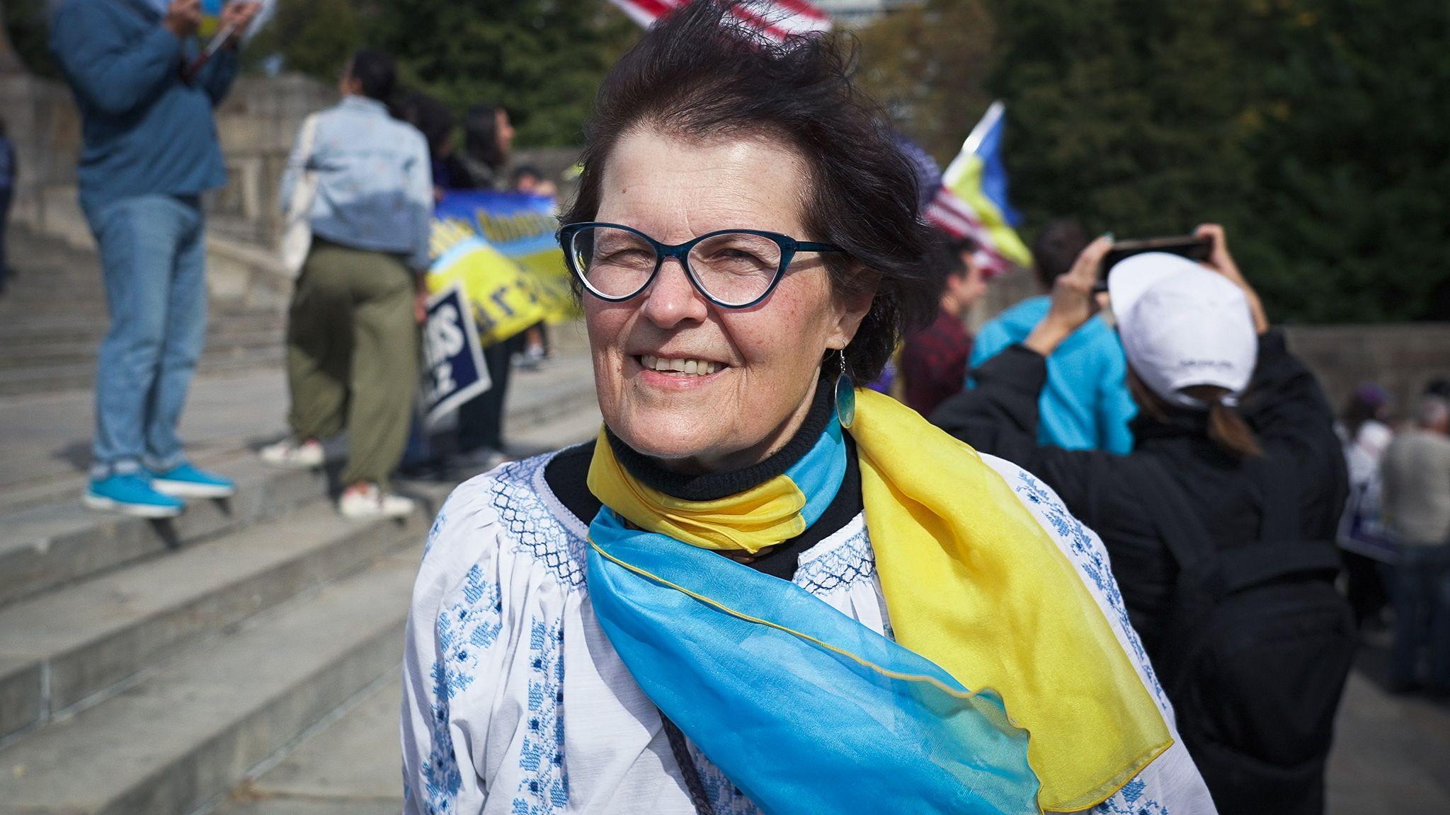 Uma mulher de óculos usando um lenço azul e amarelo sorrindo