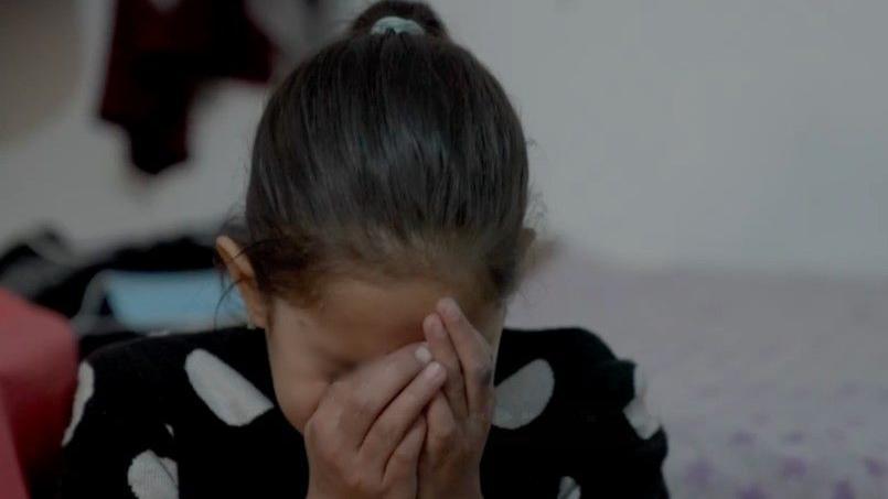 A 10-year-old Afghan girl with her face in her hands. 