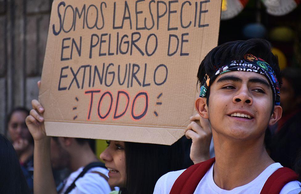 Joven en manifestaciones pidiendo acciones contra el cambio climático. Su cartel dice "somos la especie en peligro de extinguirlo todo"