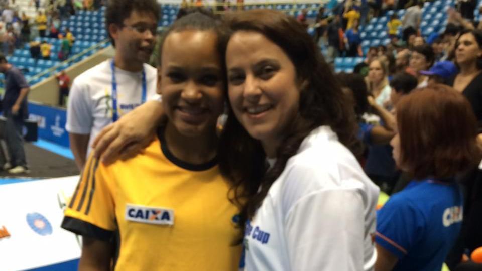 Rebeca criança e Monica se abraçam num ginásio