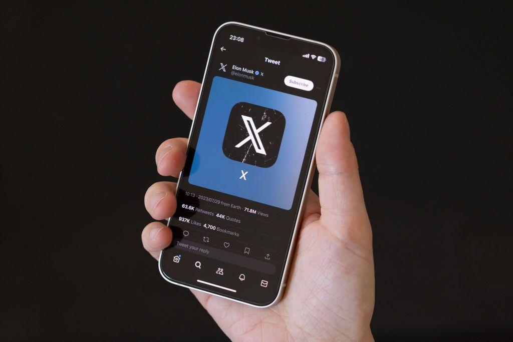 Pessoa segurando celular com logo da rede social X
