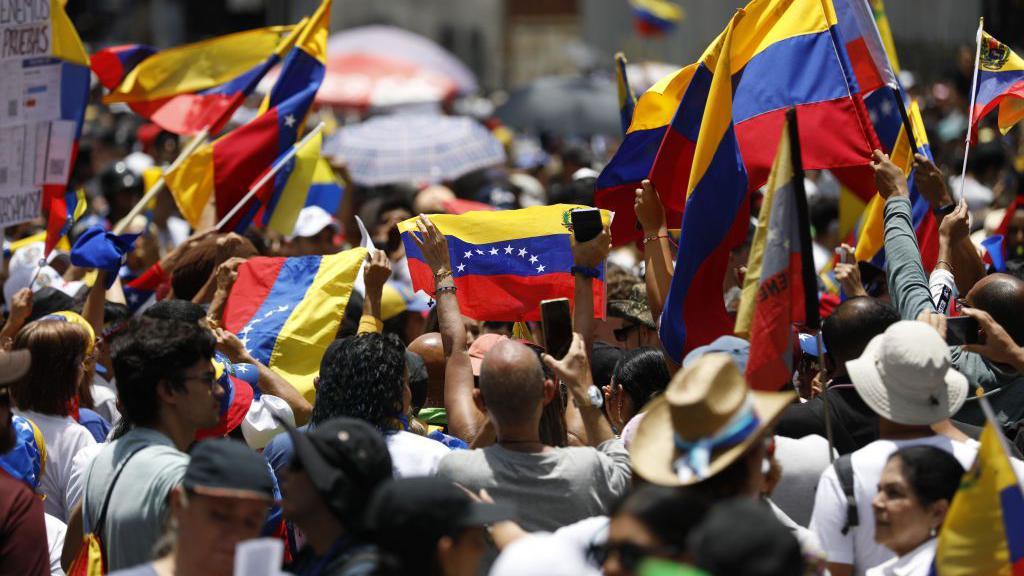 Una multitud con banderas venezolanas.