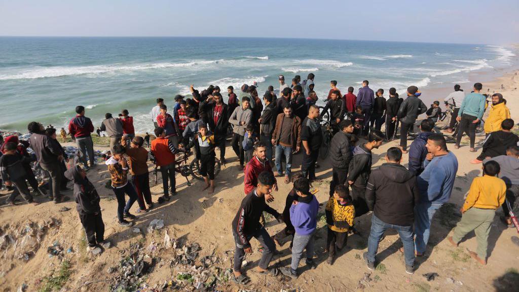 Palestinos esperan el lanzamiento aéreo de ayuda humanitaria en la playa de Deir al Balah, Gaza.