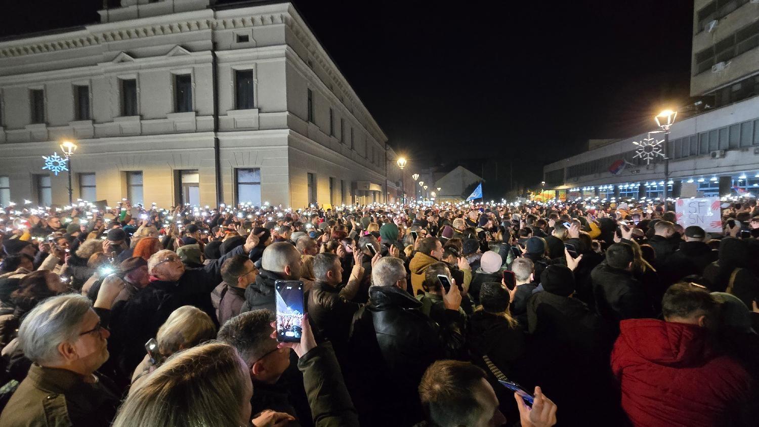 Masa ljudi na ulici tokom noći sa upaljenim telefonima