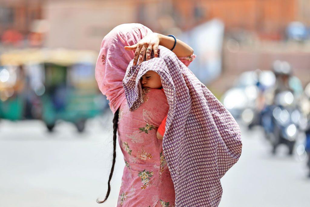 Una mujer protege a su hijo del calor con una manta