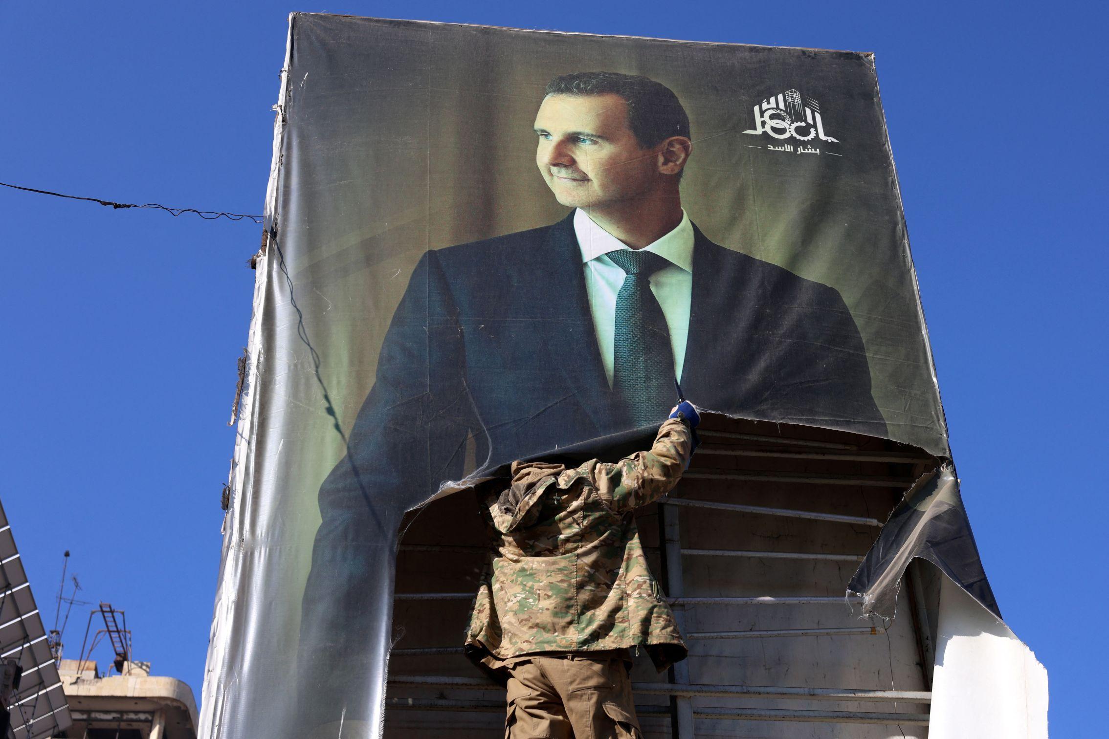 Um combatente rasgando retrato do presidente sírio Bashar al-Assad em Aleppo