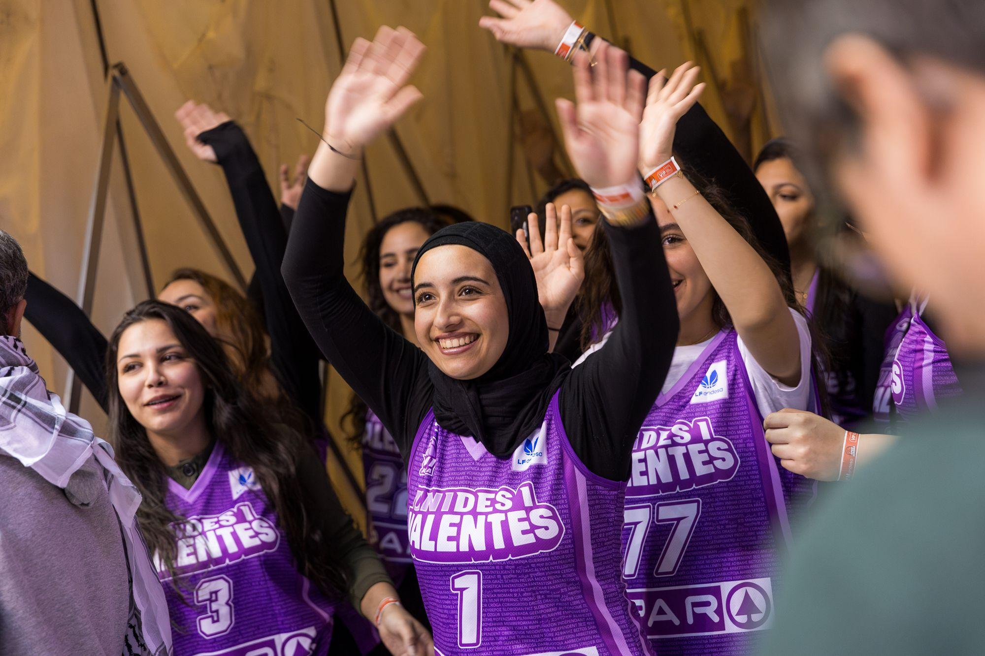 El equipo de baloncesto de mujeres se presenta en un evento en Cataluña, con uniformes especiales. Las mujeres sonríen, la primera en la foto lleva velo.