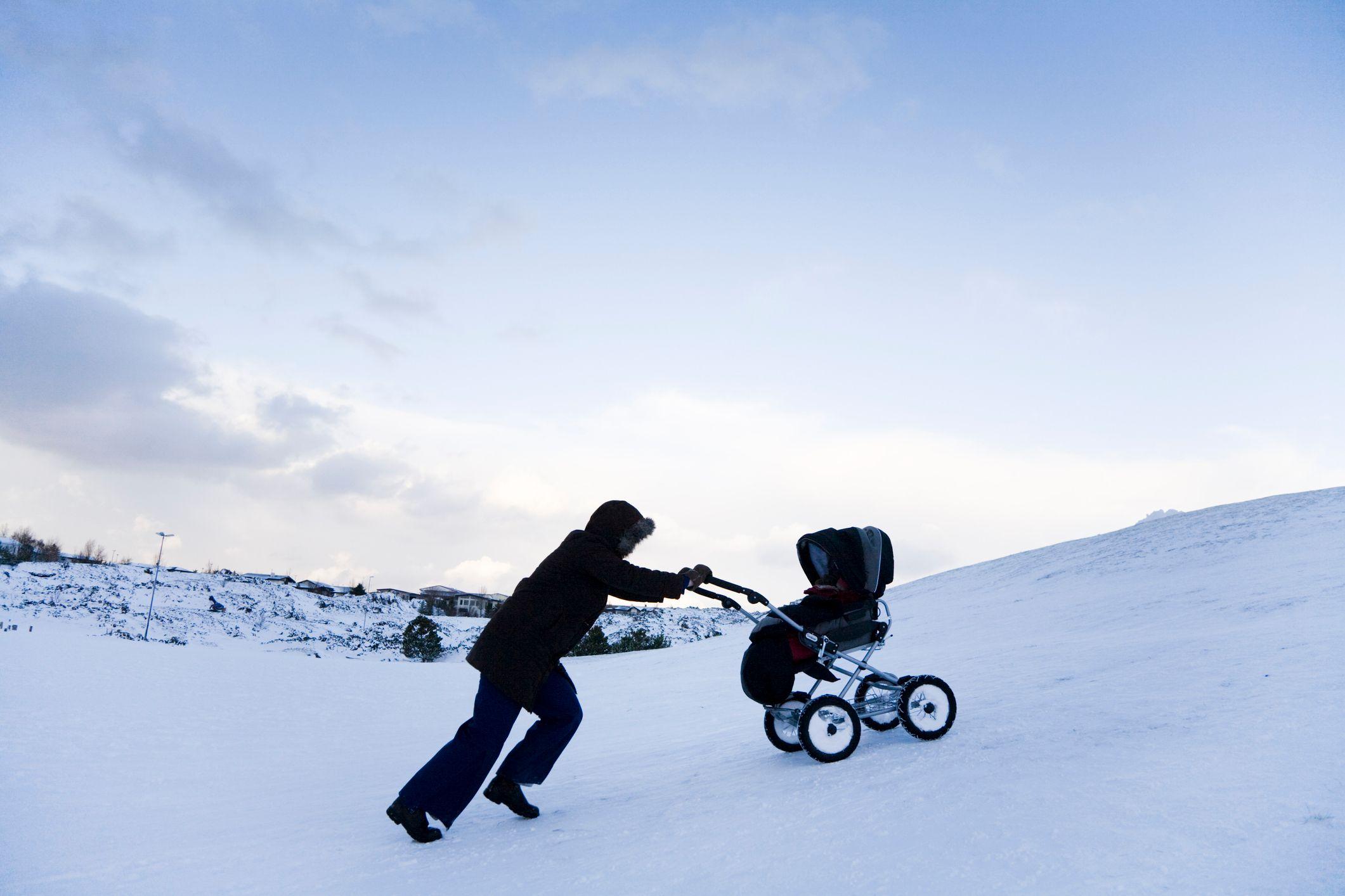 Mulher segura com carrinho de bebê na neve