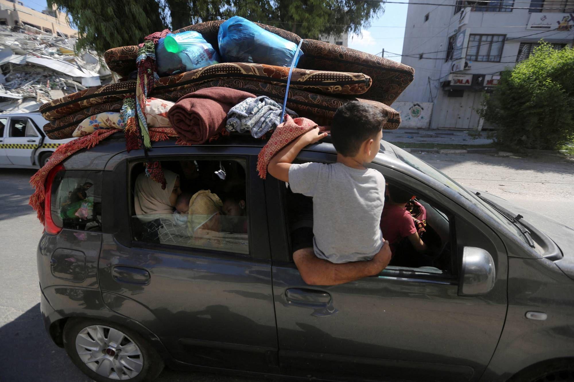Un niño montado en la ventana de un auto que evaúa Gaza