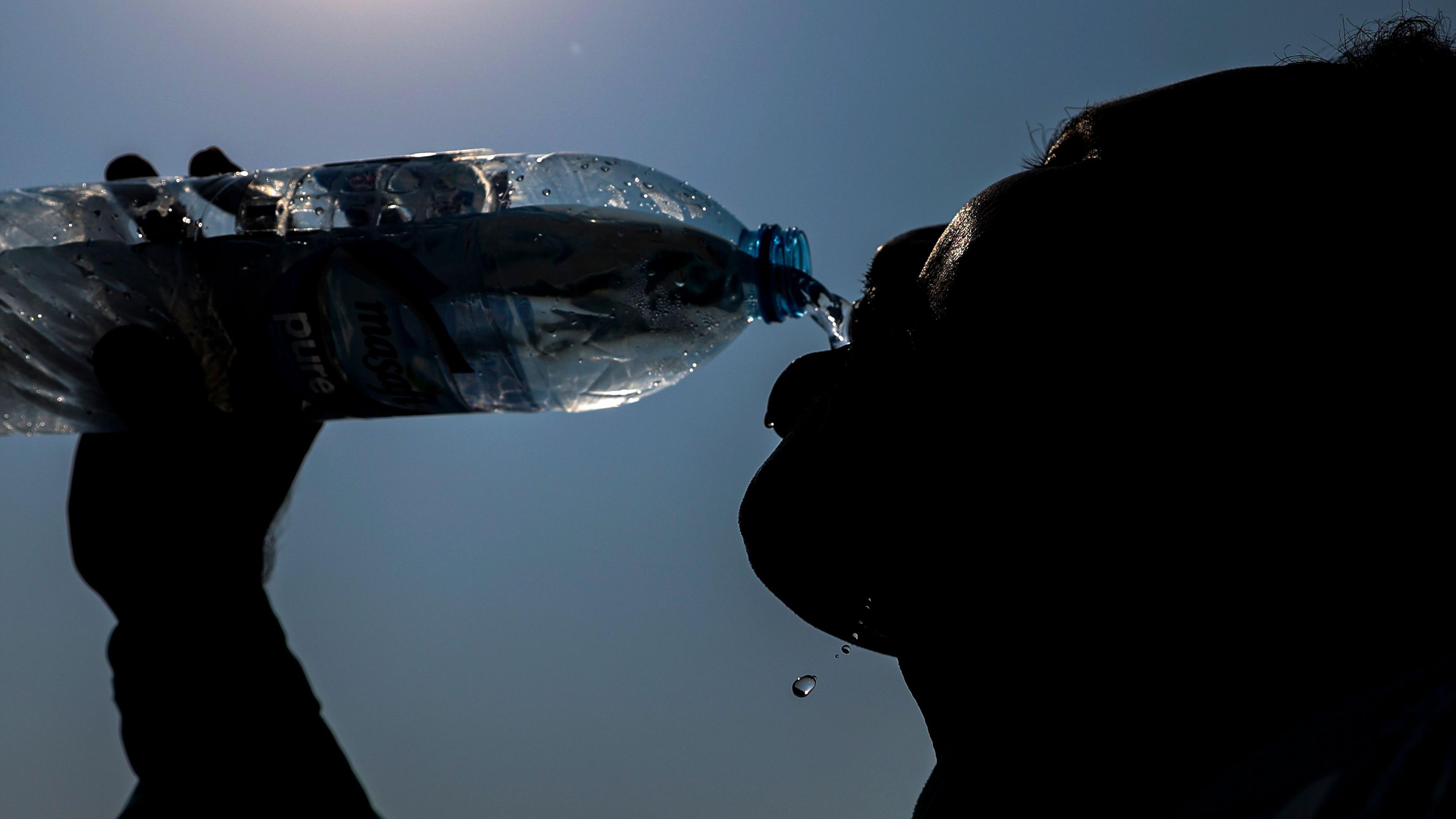 عامل يشرب الماء خلال يوم حار في دبي، الإمارات العربية المتحدة، 19 يوليو/تموز 2023. 
