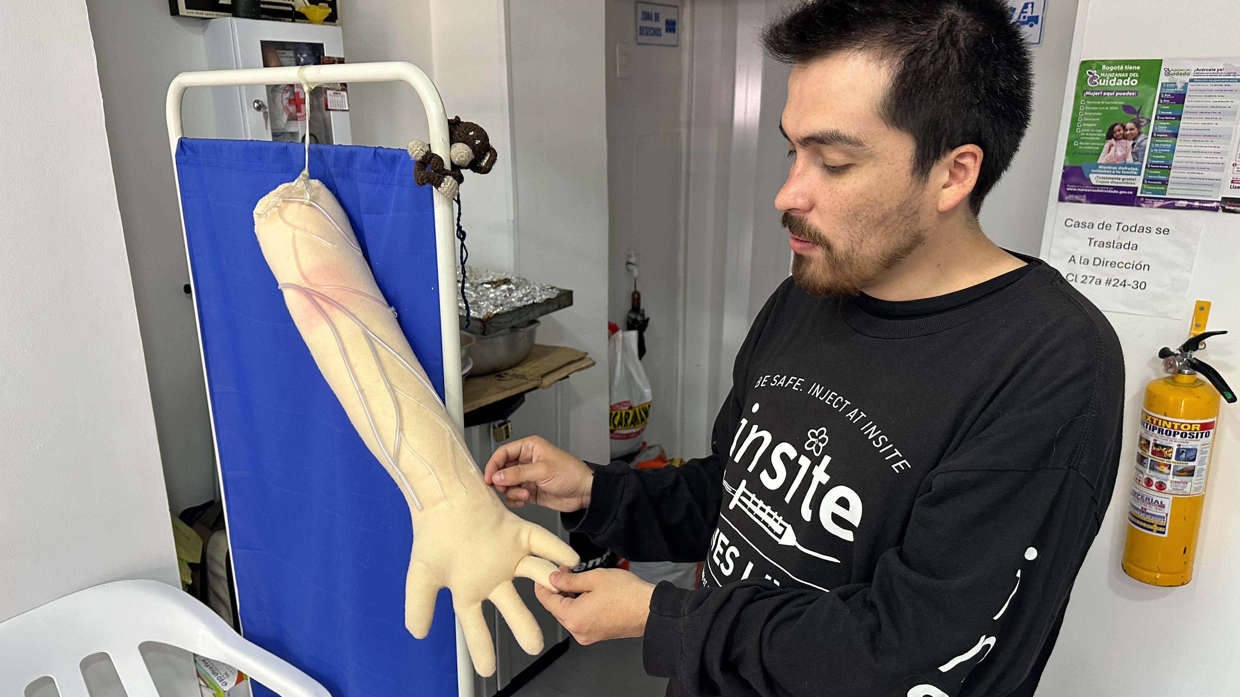 Daniel Rojas, junto a un brazo artificial con venas resaltadas que sirve de guía a los usuarios. 