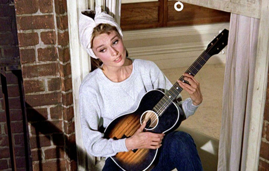 Audrey Hepburn con guitarra, cantando en la ventana