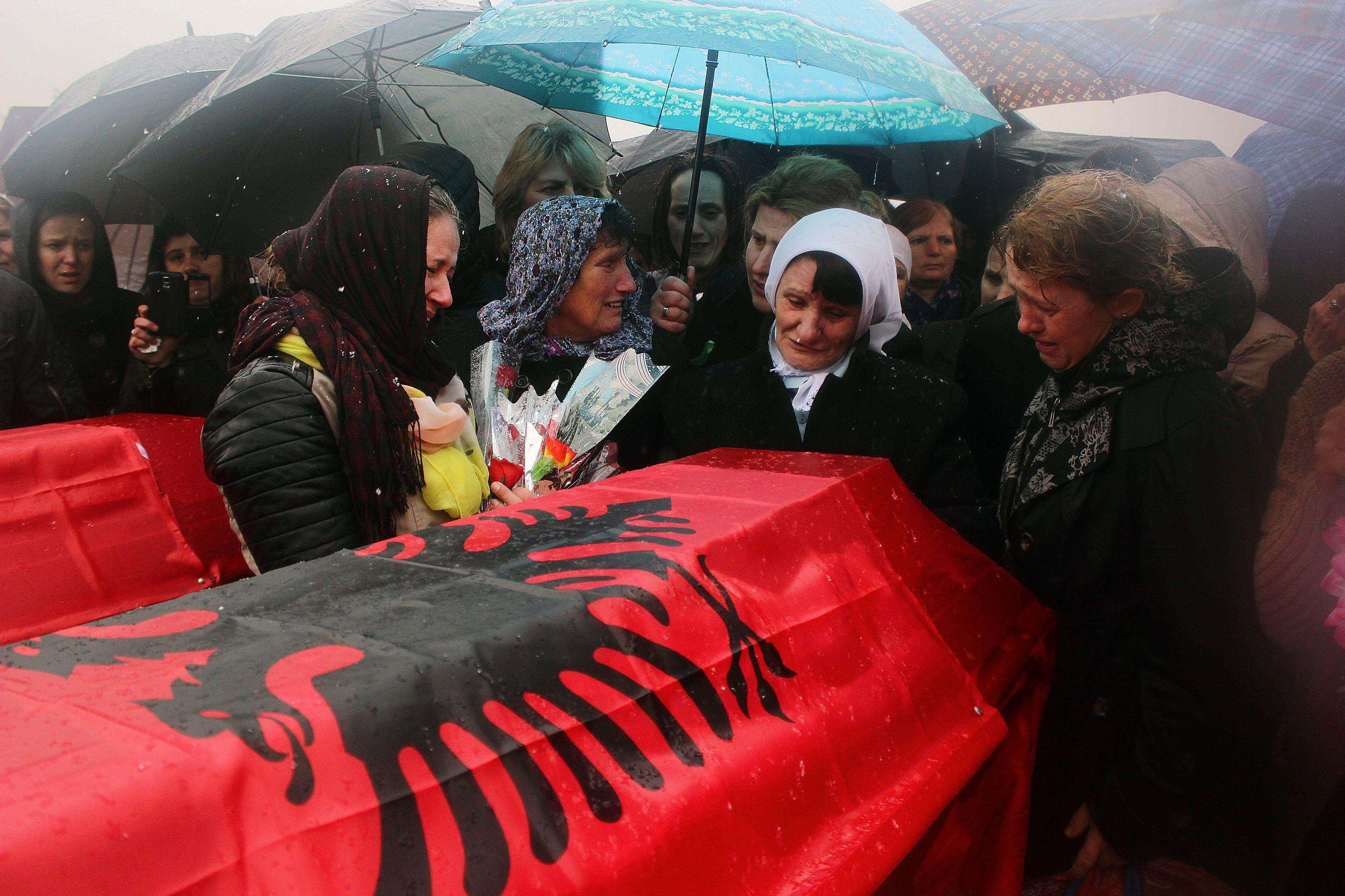 Mujeres lloran junto a un ataúd cubierto con la bandera de Albania. 