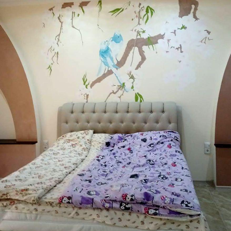 Quarto com flores de cerejeira e pombas pintadas na parede da cama