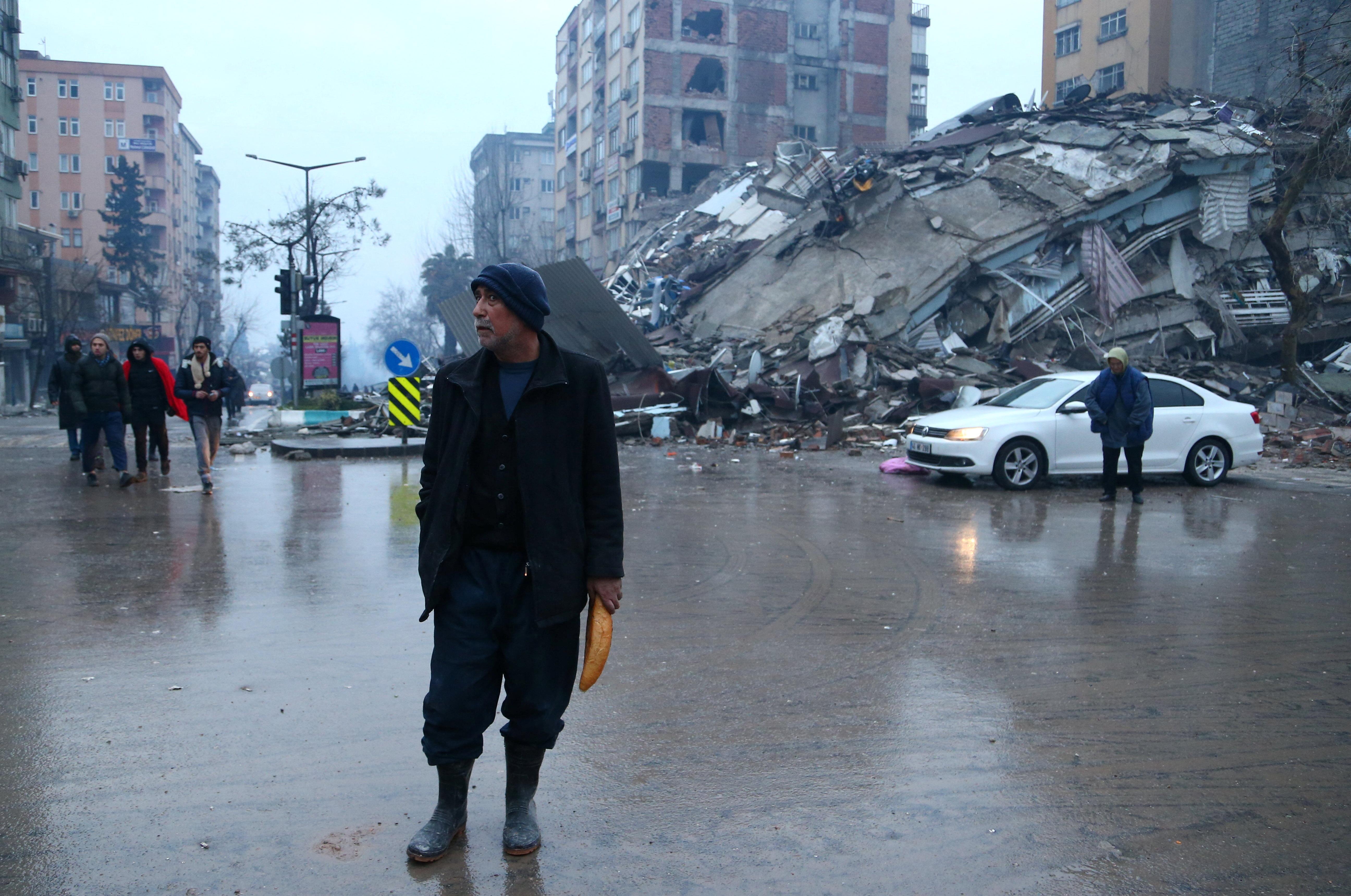 A man holding a bread walks in a street after an earthquake in Kahramanmaras, Turkey February 6, 2023. REUTERS/Cagla Gurdogan