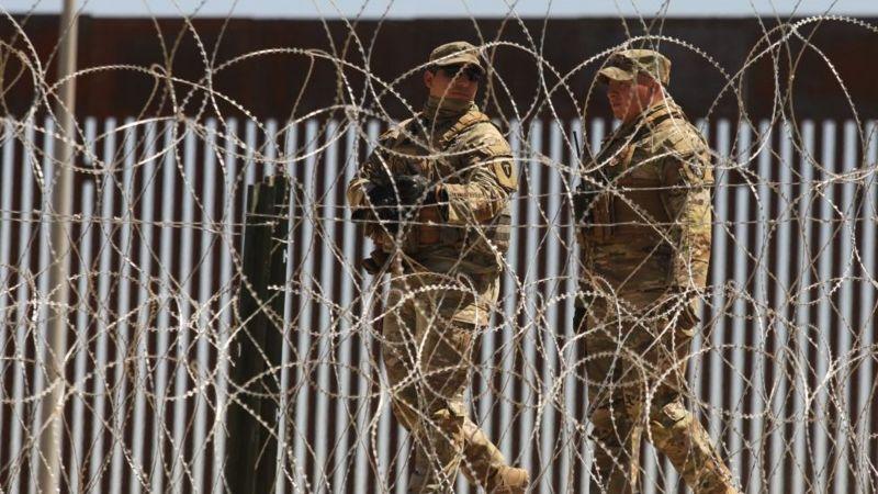 Militares na fronteira em frente a uma cerca de arame farpado