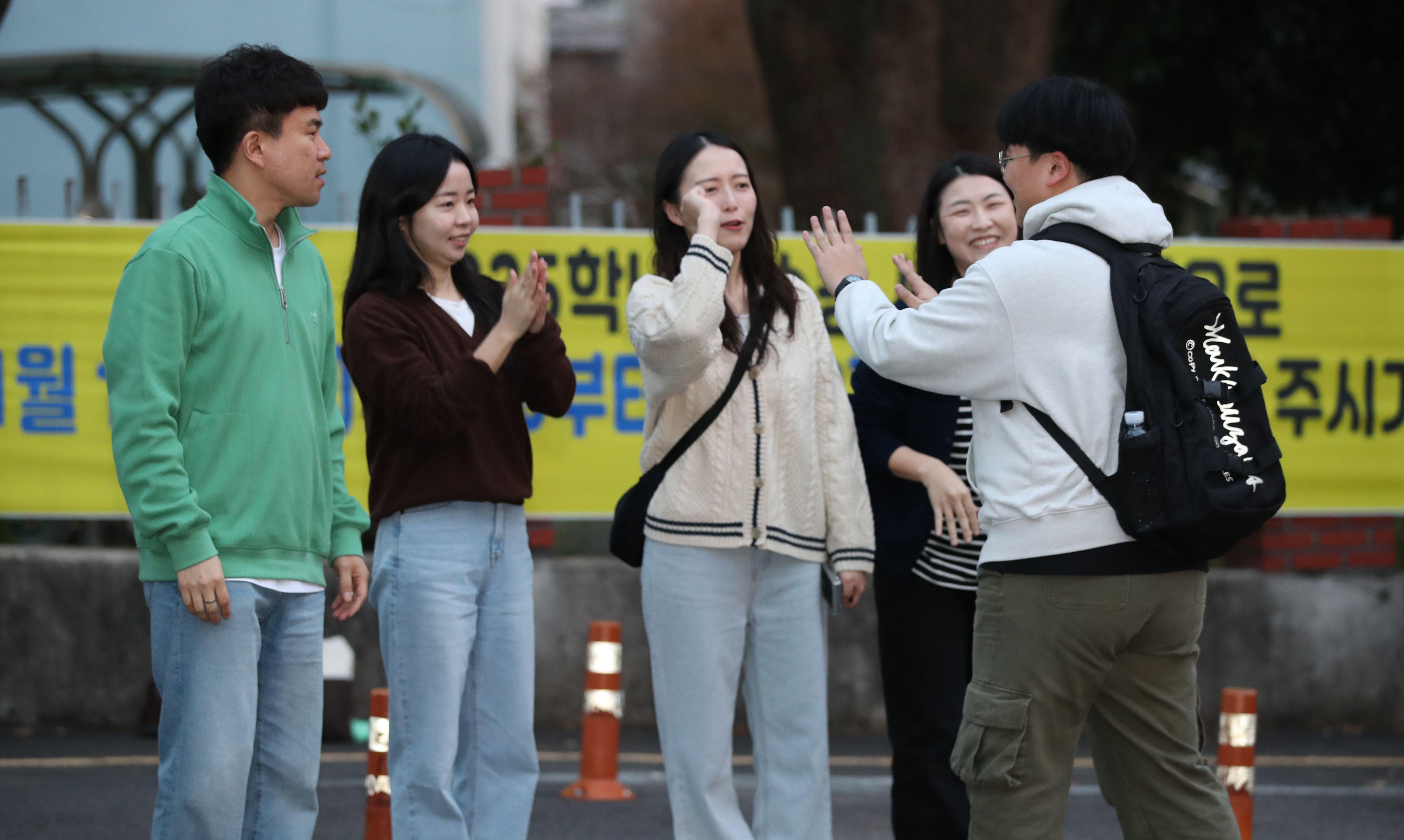 한 수험생이 네 사람의 응원을 받으며 시험장으로 들어가고 있다. 