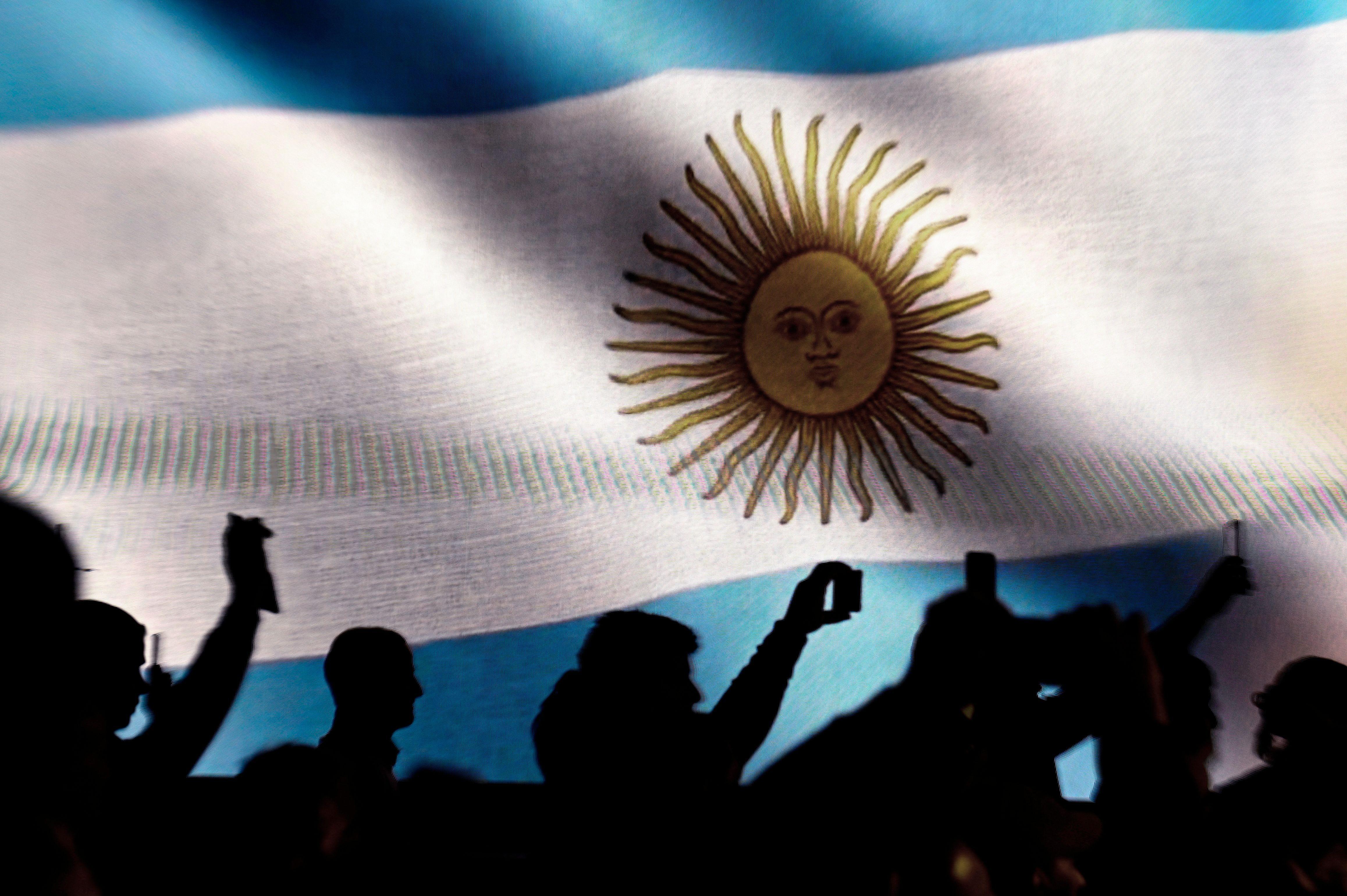 Personas delante de la bandera de Argentina
