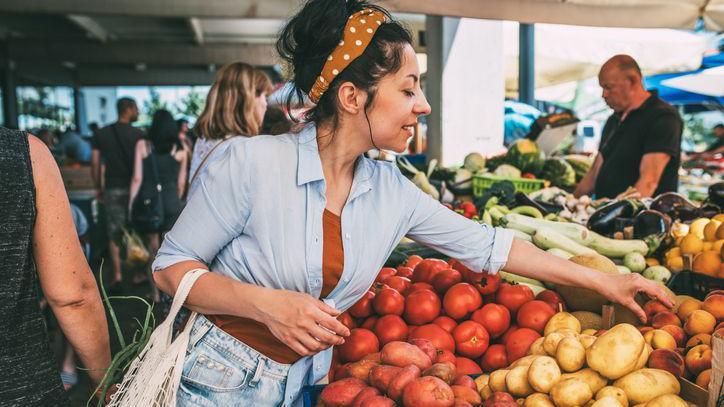 Mulher escolhendo frutas e legumes numa feira