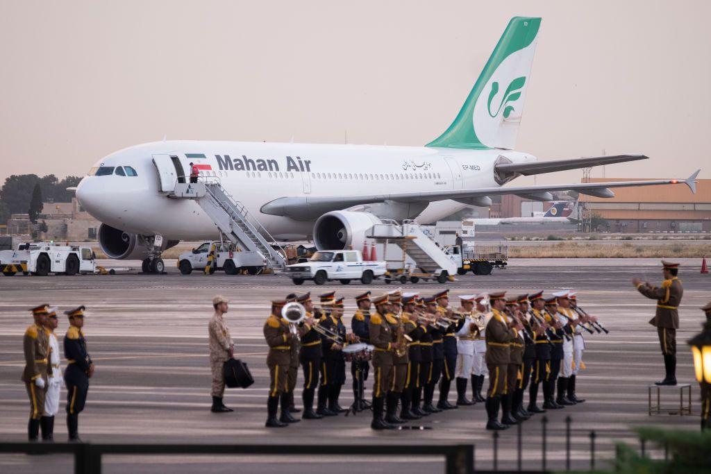 Un avión de Mahan Air, tras un grupo de militares formados en el aeropuerto de Teherán. 